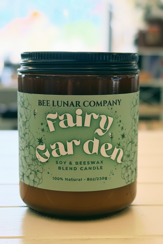 Bee Lunar Company Fairy Garden candle on a wooden table with a blurred indoor background