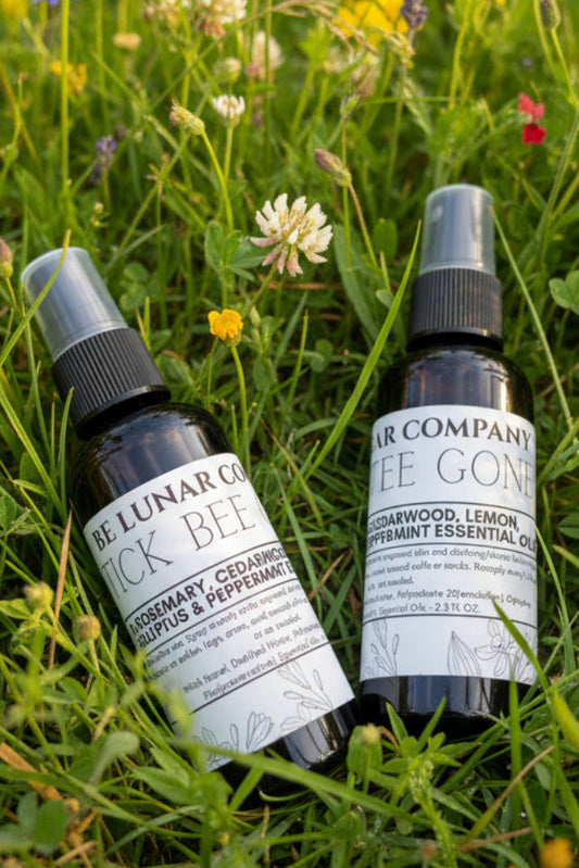 Two bottles of 'Bee Lunar Company' Tick Bee Gone spray laying in the grass. 